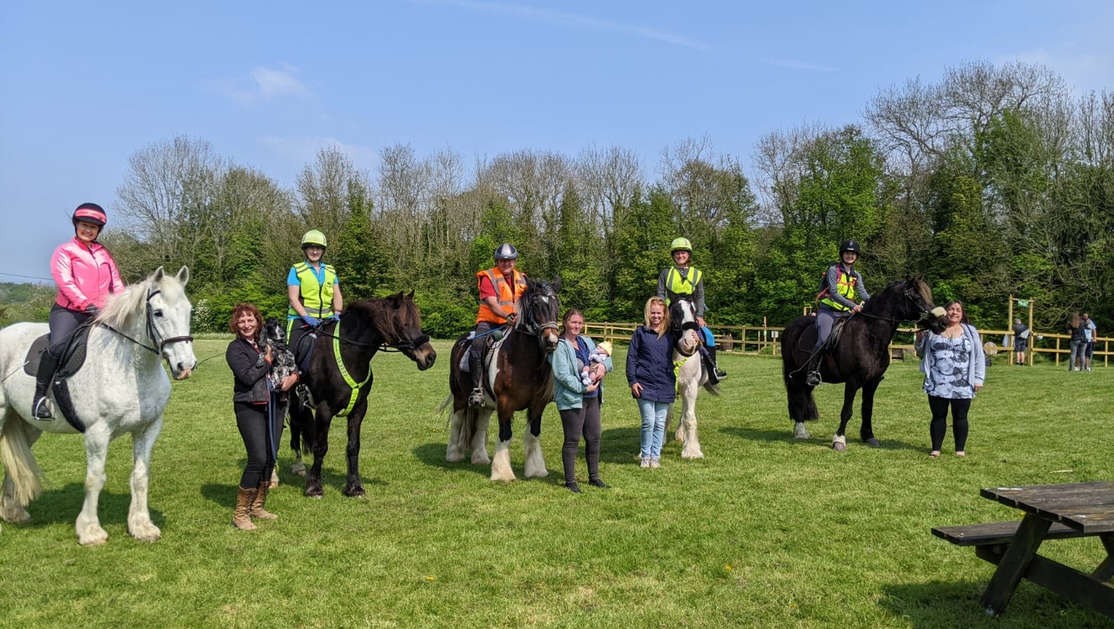 horses riders and owners standing in field